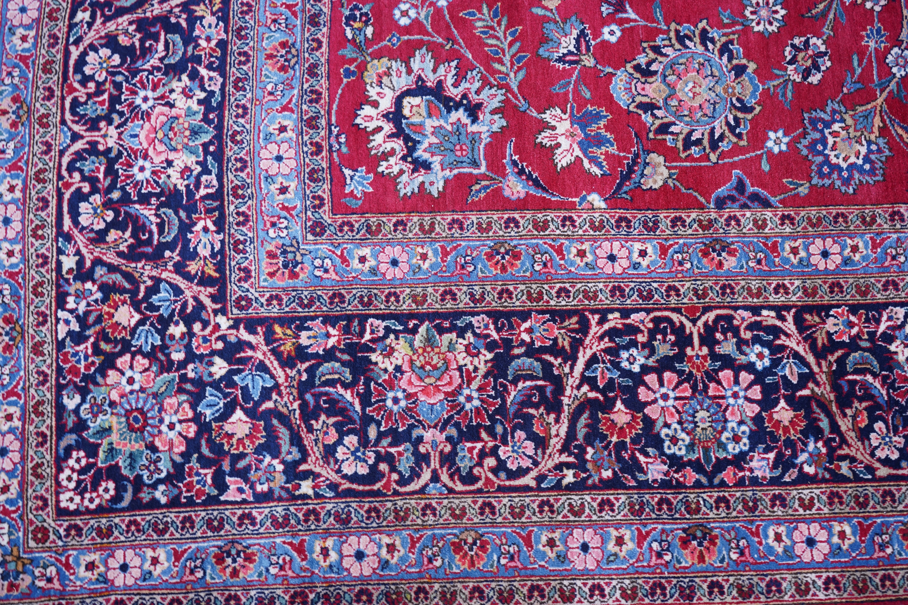 A Kashan burgundy ground carpet, woven with trailing stylised flower heads within a wide multi border, 400 x 270cm